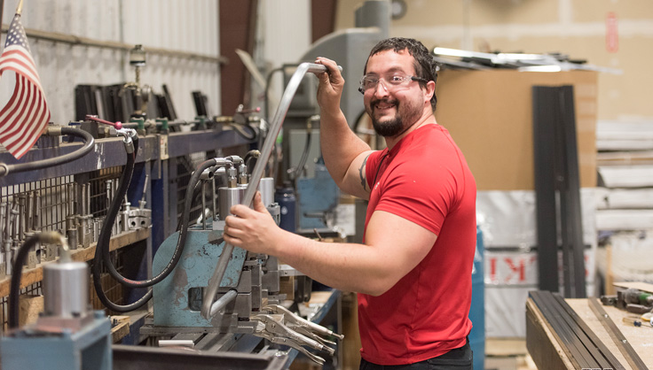 Employee in manufacturing bending aluminum for a garden cart